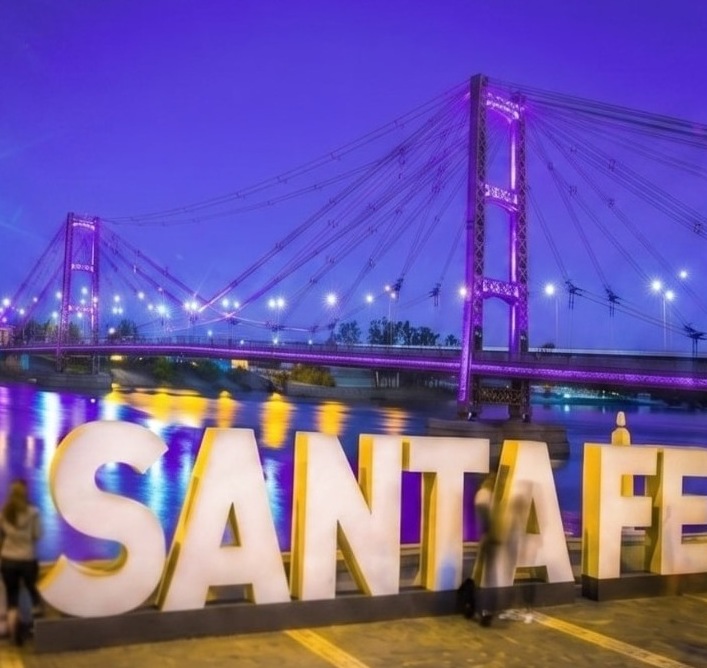Letras de Santa Fe iluminadas frente al Puente Colgante al atardecer